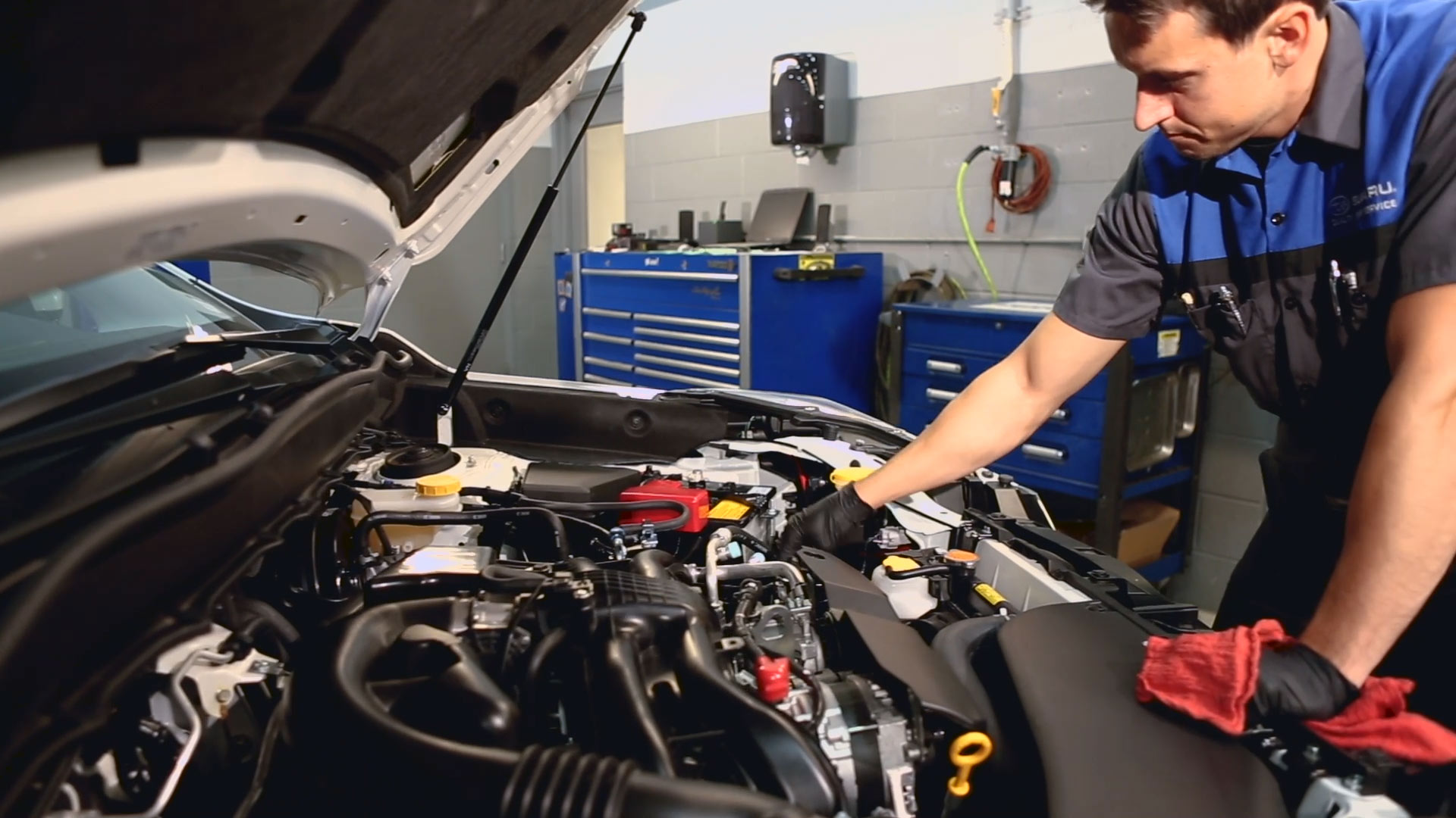 Technician working on vehicle with hood popped.